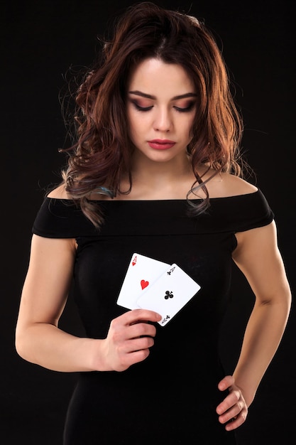 Mulher jovem segurando cartas de jogar contra um fundo preto