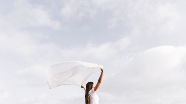 Mulher jovem, segurando, echarpe, soprar vento, contra, céu