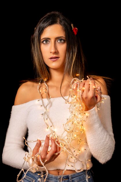 Foto mulher jovem segurando luzes de natal