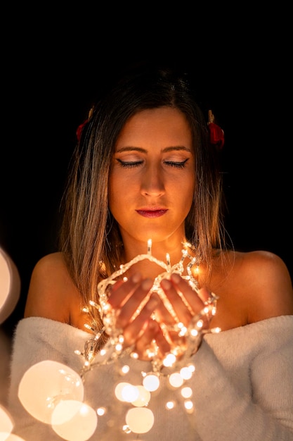 Foto mulher jovem segurando luzes de natal