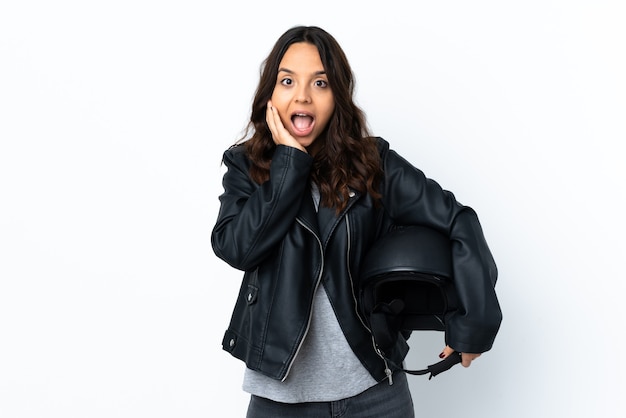 Mulher jovem segurando um capacete de motocicleta sobre um branco isolado com expressão facial de surpresa e choque