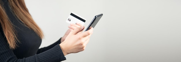 Mulher jovem segurando um cartão de crédito e um telefone inteligente