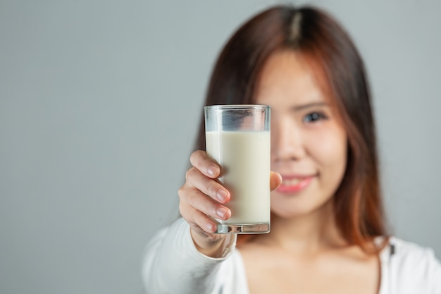 Mulher jovem segurando um copo de leite em uma superfície cinza