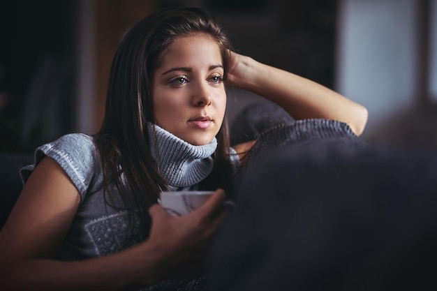 Mulher jovem segurando um copo em casa