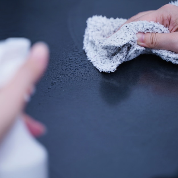 Mulher jovem segurando um frasco de spray para limpar a superfície da prateleira do gabinete de metal