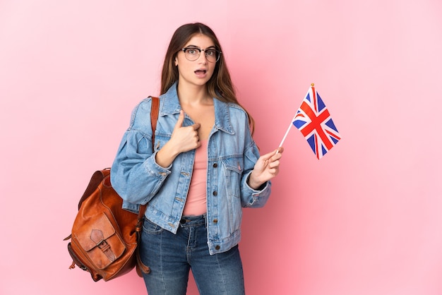 Mulher jovem segurando uma bandeira do Reino Unido em rosa com expressão facial surpresa