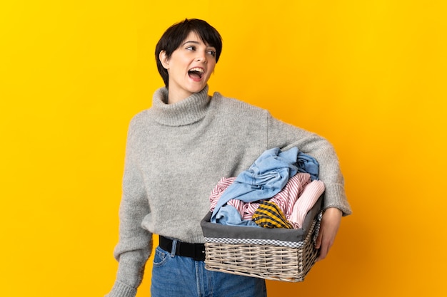 Mulher jovem segurando uma cesta de roupas rindo