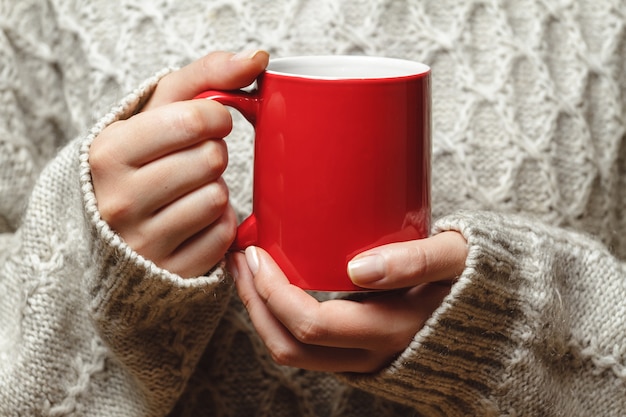 Mulher jovem segurando uma xícara de café quente nas mãos