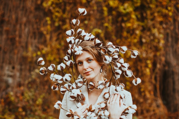 Mulher jovem sensual retrato outono. Menina segurando lindas flores de algodão na natureza.