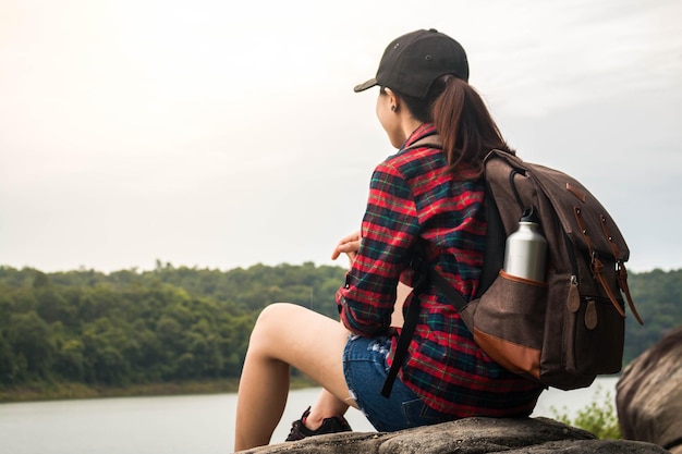 Foto mulher jovem sentada ao lado do lago contra o céu