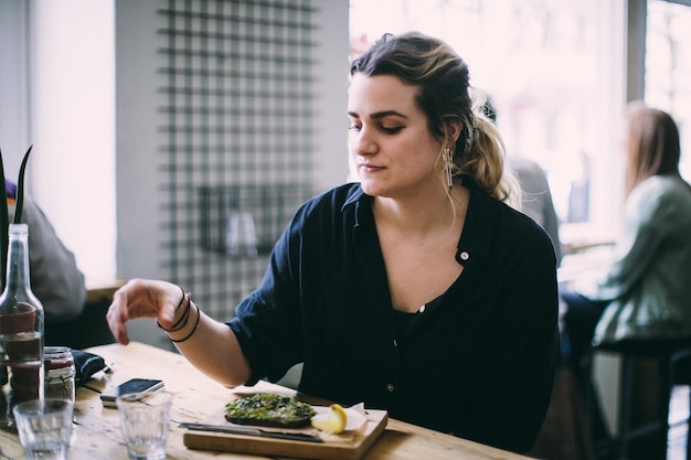 Foto mulher jovem sentada com comida na mesa em um restaurante