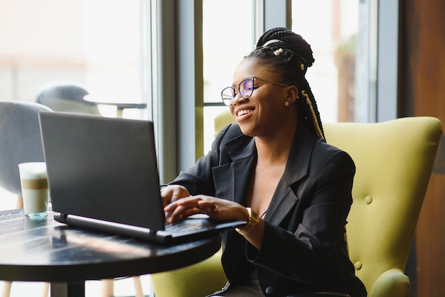 Mulher jovem sentada em um café trabalhando em um laptop