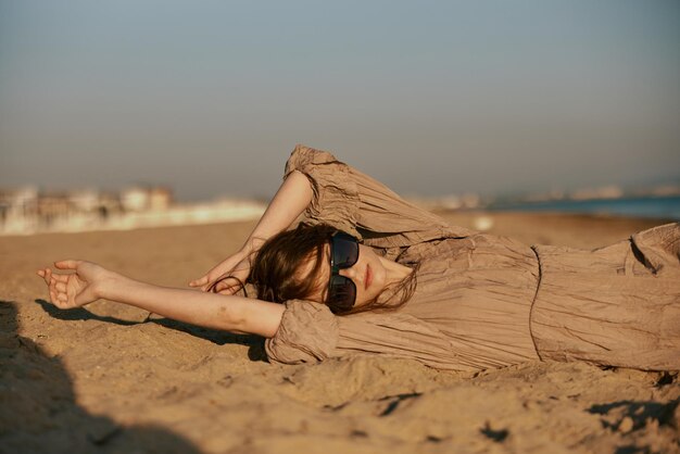 Foto mulher jovem sentada na areia na praia contra o céu