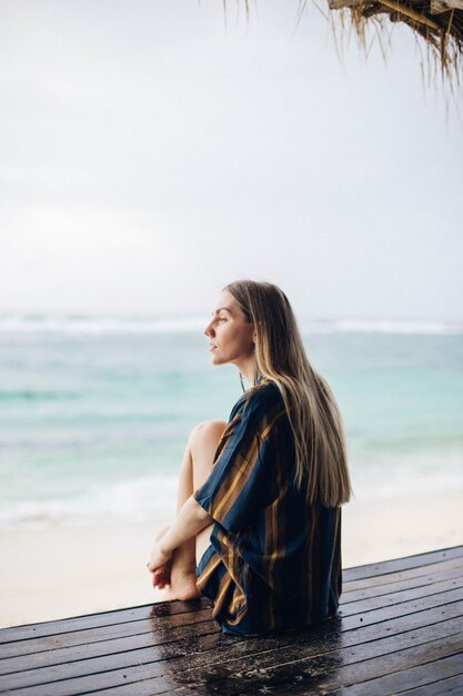 Foto mulher jovem sentada na praia contra o céu