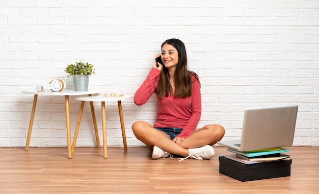 Mulher jovem sentada no chão com um laptop