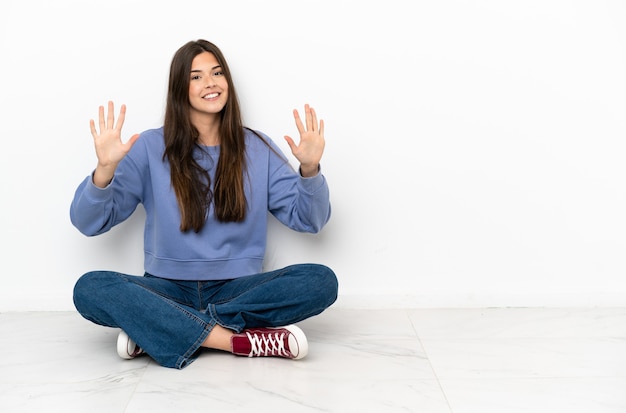 Mulher jovem sentada no chão contando dez com os dedos