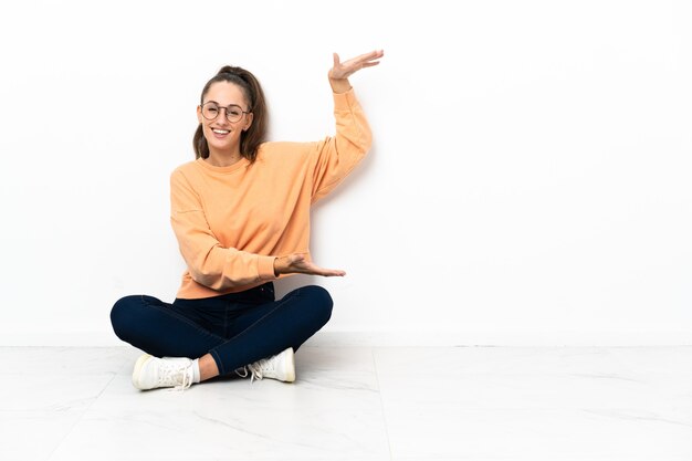 Foto mulher jovem sentada no chão segurando copyspace para inserir um anúncio