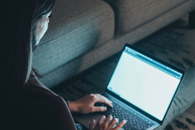 Foto mulher jovem sentada no tapete em casa trabalhando e relaxando até tarde em casa usando espaço de cópia de laptop garota casual à luz da tela tecnologia e conceito de trabalho mulher de atividade de lazer interior