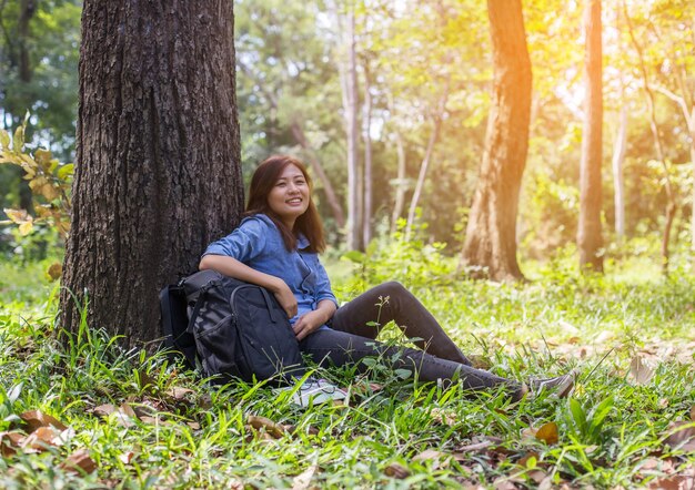 Mulher jovem sentada no tronco de uma árvore na floresta