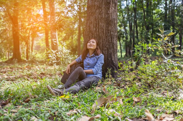 Foto mulher jovem sentada no tronco de uma árvore na floresta