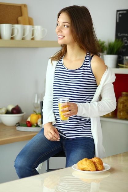 Mulher jovem sentada perto da mesa na cozinha
