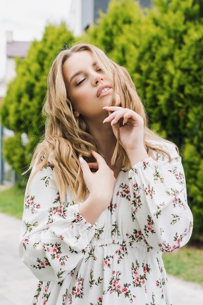 Mulher jovem sexy em um vestido de verão Uma modelo posa em um parque em um dia ensolarado Maquiagem e penteado