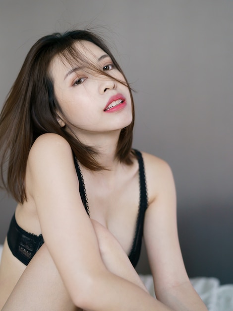 Mulher jovem sexy lingerie preta sensual, posando em cima da cama.