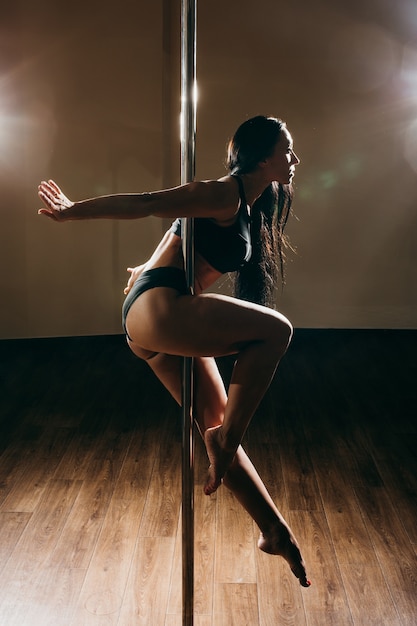 Foto mulher jovem sexy pole dance, fundo escuro