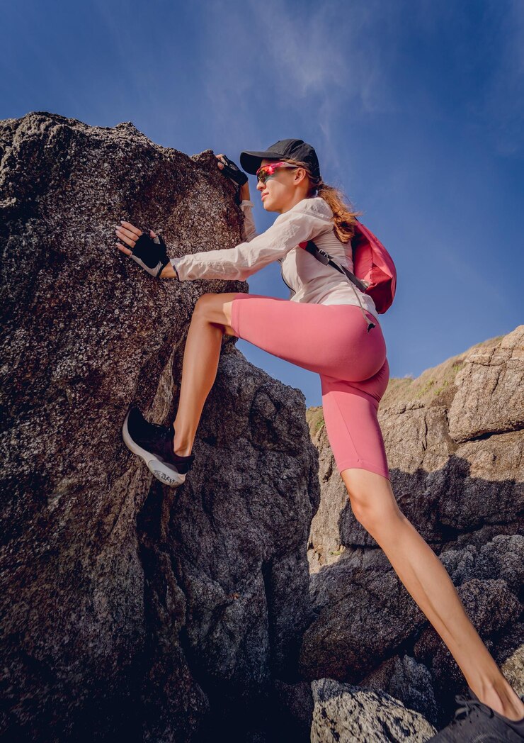 Foto mulher jovem sobe ao topo das montanhas perto do oceano