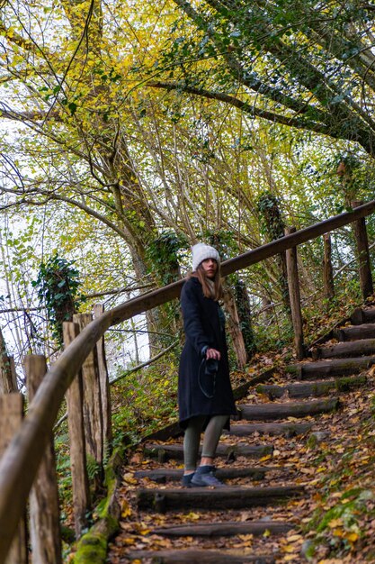 Mulher jovem sobe escadas da floresta de outono