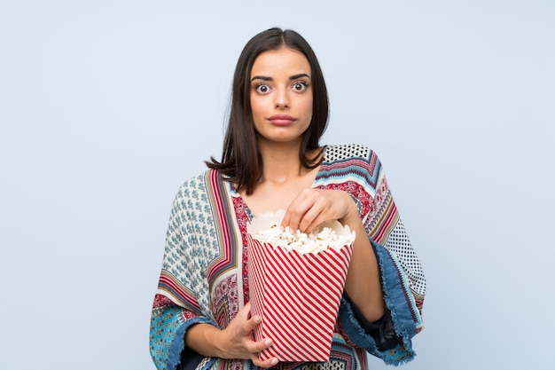 Mulher jovem, sobre, isolado, parede azul, comer, pipocas