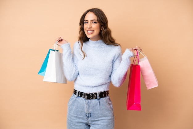 Mulher jovem, sobre, parede, segurando sacolas, e, sorrindo