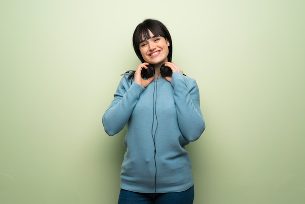 Mulher jovem, sobre, parede verde, com, fones