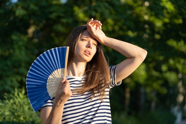 Foto mulher jovem sofre de insolação ao ar livre menina infeliz se sentindo mal com temperatura quente toque na testa