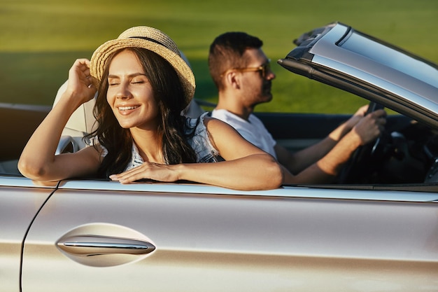 Mulher jovem sonhadora com os olhos fechados andando de cabriolet com namorado