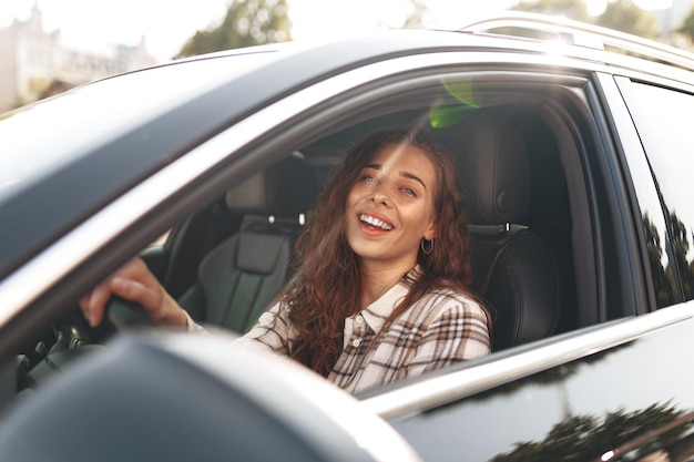 Mulher jovem sorridente a conduzir um carro na cidade