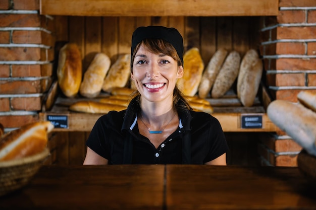 Foto mulher jovem sorridente a trabalhar numa padaria.