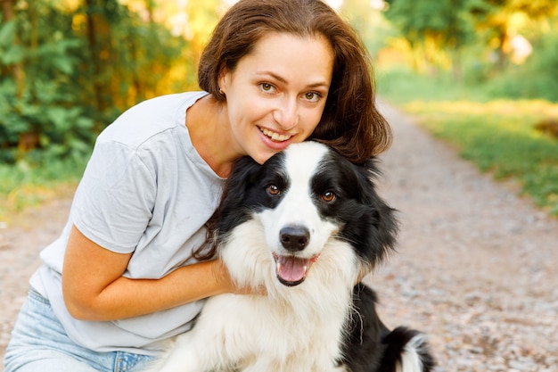 Mulher jovem sorridente brincando com filhote de cachorro fofo border collie no verão ao ar livre