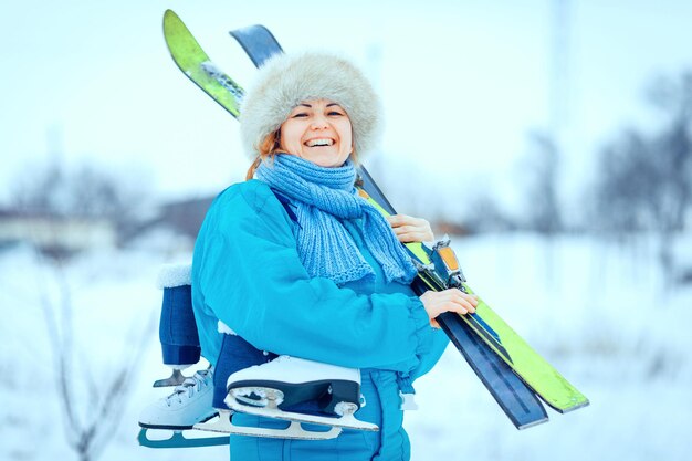 Mulher jovem sorridente carregando um par de patins de gelo, esquiando