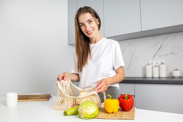 Mulher jovem sorridente, colocando as compras da loja na cozinha