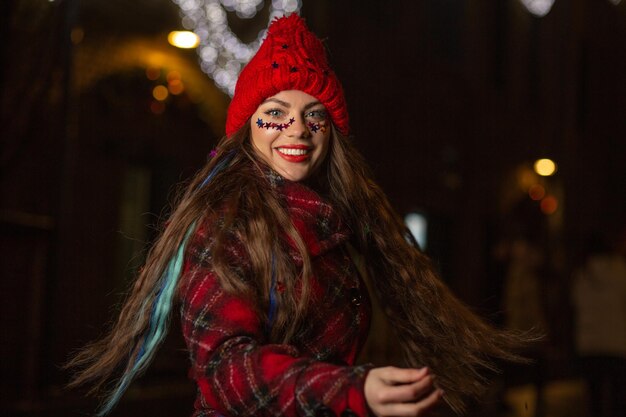 Mulher jovem sorridente com cabelos esvoaçantes se divertindo na feira de Natal