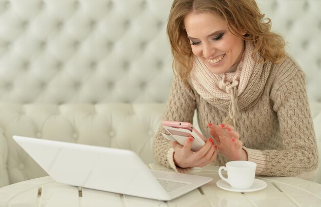 Mulher jovem sorridente com laptop e smartphone