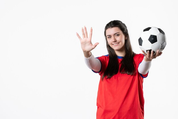 Mulher jovem sorridente com vista frontal em roupas esportivas e bola de futebol