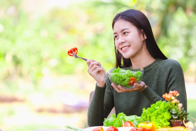 Mulher jovem sorridente comendo salada em um café ao ar livre