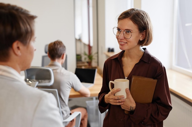 Mulher jovem sorridente conversando com um colega