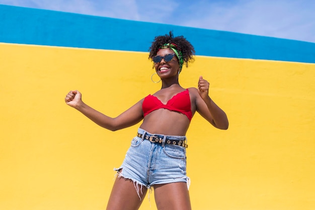 Mulher jovem sorridente dançando contra a parede amarela
