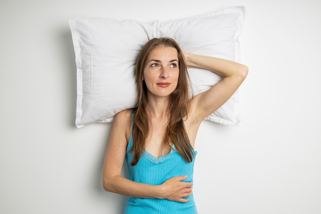 Mulher jovem sorridente deitada em um travesseiro em um fundo branco Vista superior plana