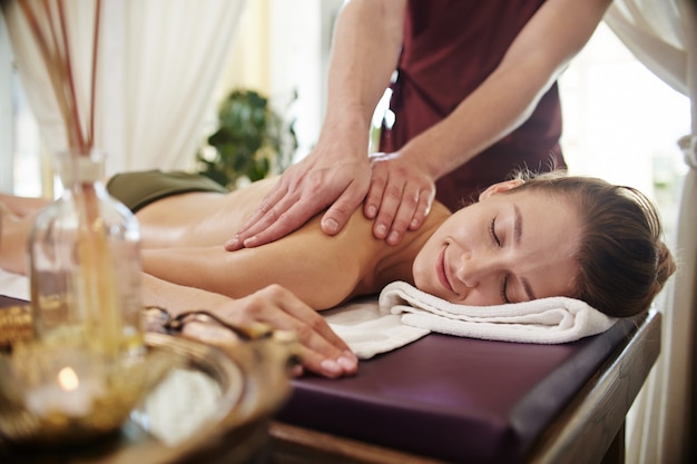 Mulher jovem sorridente, desfrutando de massagem no SPA