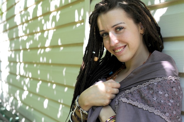 Mulher jovem sorridente e feliz com dreadlocks ao ar livre perto de sua casa