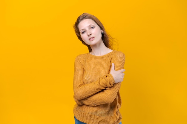 Mulher jovem sorridente em suéter amarelo posando isolado em amarelo pastel